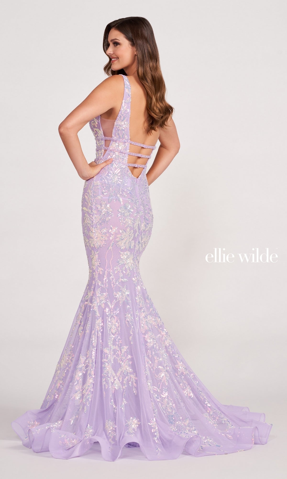 Woman wearing a Banded-Waist Long Sequin Mermaid Prom Dress featuring a lavender hue, floor-length design, sleeveless style, floral embellishments, and open strappy back, posed against a plain background.